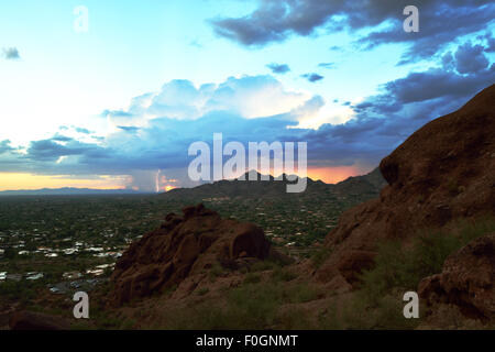 Monsoon rains fall in the distance with lightning at sunset Stock Photo