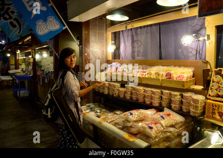 Thai woman buying traditional Japanese food (seafood and sushi) at Kuroshio Market on July 8, 2015 in Wakayama, Japan Stock Photo