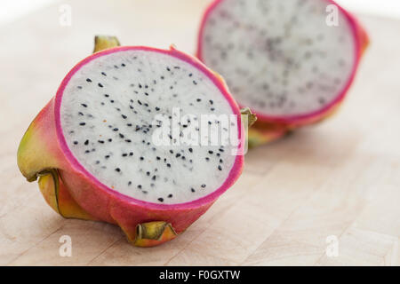 A sliced dragon fruit on a wooden surface photographed with window light. Stock Photo