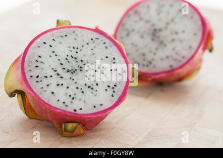 A sliced dragon fruit on a wooden surface photographed with window light. Stock Photo