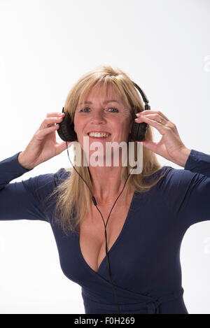 Attractive woman holding headphones to her ears Listening to music Stock Photo