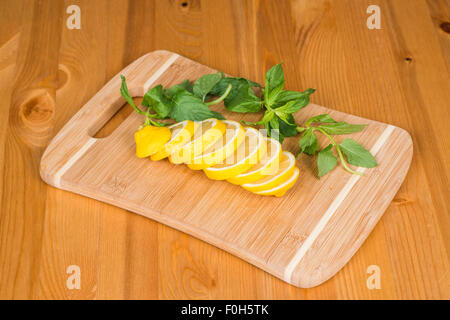 Sliced lemon with some mint on a cutting board Stock Photo