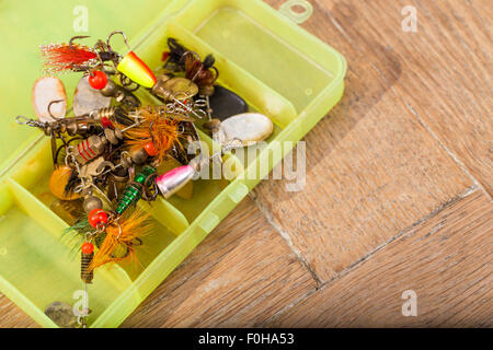 closeup heaps of fishing bait lures in box on wooden background Stock Photo