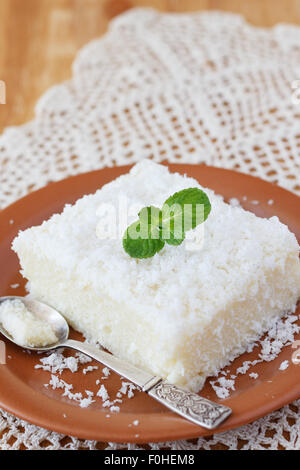 Brazilian traditional dessert: sweet couscous (tapioca) pudding (cuscuz doce) with coconut and mint on plate with spoon Stock Photo