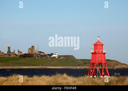 The Herd Groyne lighthouse stands in front of the Tynemouth Priory and the Collingwood Memorial at Tynemouth, England. The prior Stock Photo