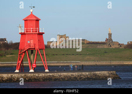 Herd Groyne lighthouse in South Shields, England. The lighthouse stands by the mouth of the River Tyne and Tynemouth Priory in t Stock Photo