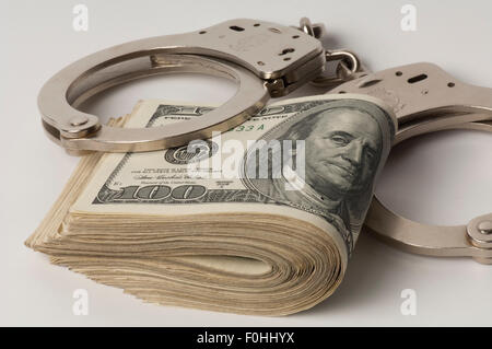 handcuffs on wad of United States $100 dollar bills Stock Photo