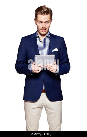 Young man is gesturing and reading from digital tablet. Isolated on white background. Stock Photo