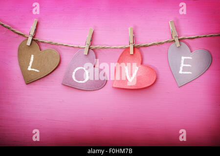 Love message on paper hearts over pink wooden board Stock Photo