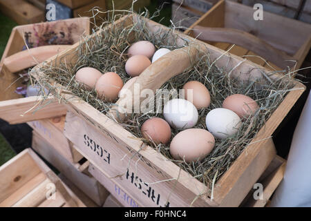 Eggs nestling on straw in a wooden basket Stock Photo