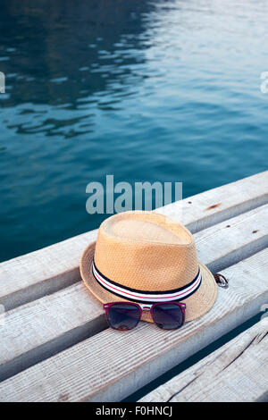 Sunglasses, flip-flops and hat on the wooden texture in summer. Stock Photo