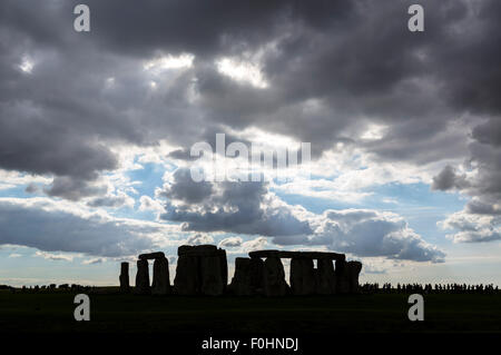 Line of visitors silhouetted next to the stones, Stonehenge, near Amesbury, Wiltshire, England, UK