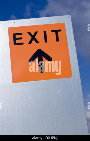 Orange exit sign against the blue sky Stock Photo