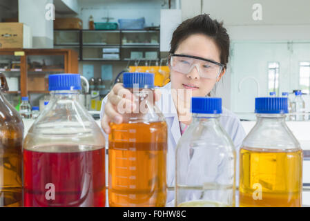 Asian scientist selecting bottle in shelf at laboratory Stock Photo