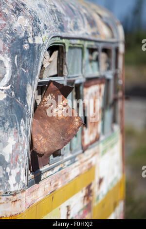 Detail of rusted old colored school bus with broken windows abandoned in the countryside in the North of Argentina near San Juan Stock Photo