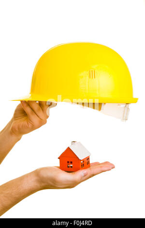 Hand holding yellow helmet over a small house Stock Photo