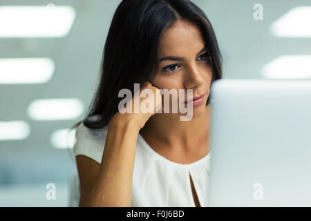 Portrait of a young beautiful businesswoman working on laptop in office Stock Photo