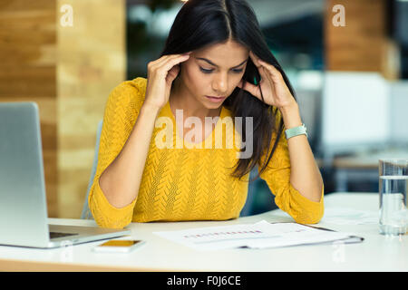 Portrait of a young casual businesswoman reading documents in office Stock Photo