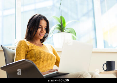 Happy casual businesswoman sitting on office chair with laptop in office Stock Photo
