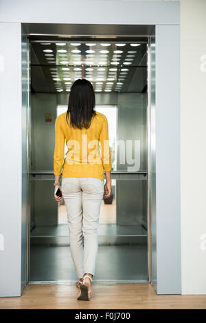 Back view portrait of a woman going in elevator indoors Stock Photo
