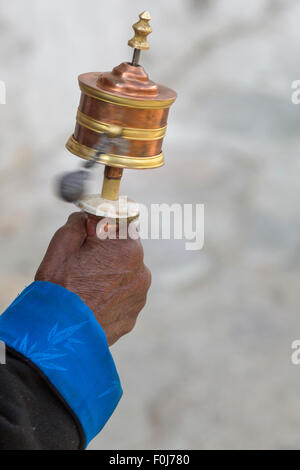 Detail of the hand of an old woman praying with prayer roll at the Palkhor Monastery in Lhasa. Stock Photo