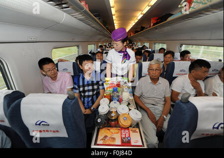 (150817) -- HARBIN, Aug. 17, 2015 (Xinhua) -- A stewardess serves passengers on the high-speed train D7989, northeast China's Heilongjiang Province, Aug. 17, 2015. China's northernmost high-speed railway between two cities of Harbin and Qiqihar in Heilongjiang started operation on Monday. With a designated speed of 250 kilometers per hour and eight stops, the trip from Harbin to Qiqihar was reduced from three hours to 85 minutes. The trains have been modified to adapt to temperatures as low as minus 40 degrees Celsius and resist adverse weather, such as strong winds, heavy rain, snow and fog.  Stock Photo