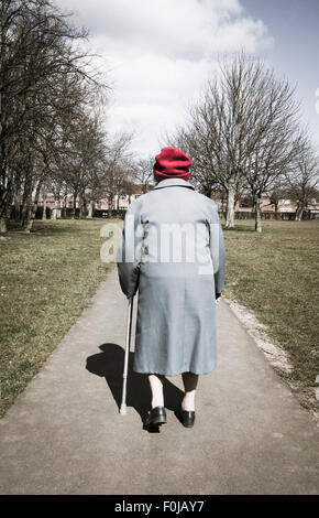 Ninety year old lady walking with stick in public park. England. UK Stock Photo