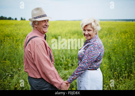Happy seniors holding by hands in the field Stock Photo