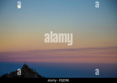 A fantasy cloudscape textured with the moon at the top of the Etna. The sky is reddish with bits of pink Stock Photo