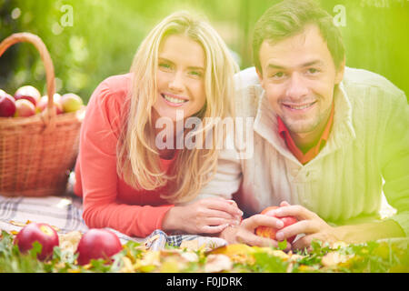 Happy young couple lying on grass in park Stock Photo