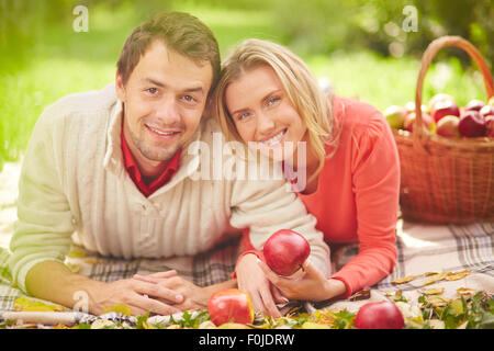 Happy young couple with red apples relaxing in natural environment Stock Photo