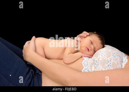 Seven days old little baby boy lying on his mother's belly Stock Photo