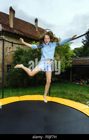 Cute teenage girl jumping on trampoline, childhood concept