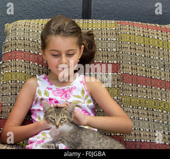 Little girl and her cute cat sitting on sofa Stock Photo