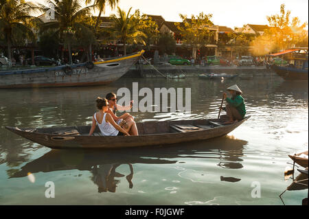 Vietnam travel, view of a young european couple taking a selfie photo while enjoying a boat-ride on the Thu Bon river in Hoi An, Central Vietnam. Stock Photo