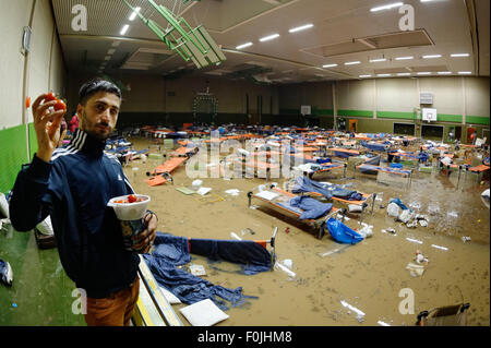 Gross Schneen, Germany. 17th Aug, 2015. A Syrian refugee stands in a flooded gymnasium which serves as an emergency shelter in Gross Schneen, Germany, 17 August 2015. About 200 refugees had to be evacuated from the shelter on Sunday night. Water seeped into the building after heavy rain showers. The refugees were taken to a school nearby. Photo: Swen Pfoertner/dpa/Alamy Live News