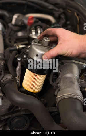 A car mechanic fits an oil filter to a car during general maintenance