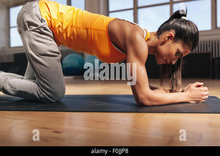 Young woman exercising on fitness mat. Strong young female athlete doing core workout in gym. Stock Photo
