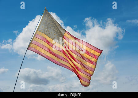 Faded American flag flying against a blue sky Stock Photo