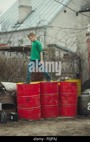 boy walks on the barrels from oil Stock Photo