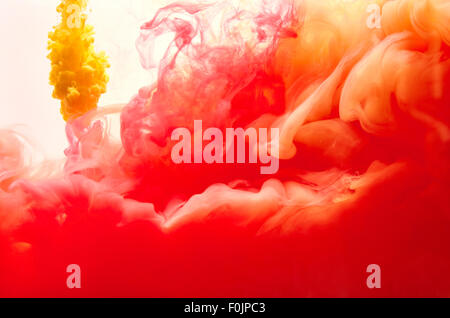 Red and yellow inks making clouds in water Stock Photo