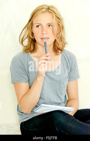 Young woman thinking over making notes in notebook Stock Photo