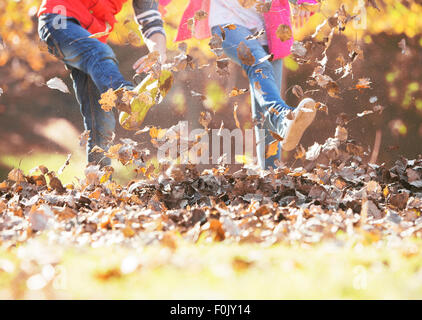 Boy and girl kicking in autumn leaves Stock Photo