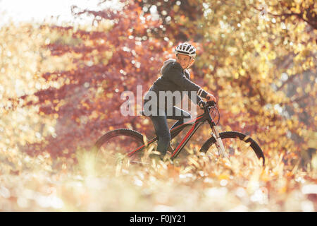 Boy bike riding in woods with autumn leaves Stock Photo