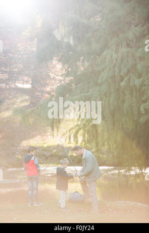 Father and sons preparing fishing rods in woods Stock Photo