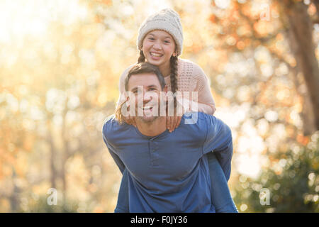 Portrait enthusiastic father piggybacking daughter outdoors Stock Photo