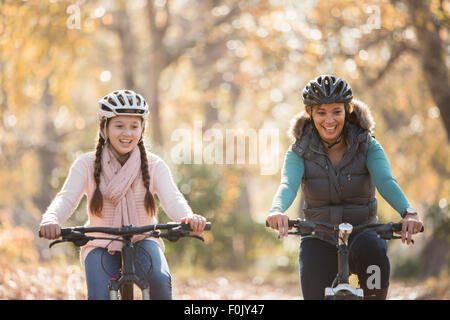 Smiling mother and daughter bike riding outdoors Stock Photo