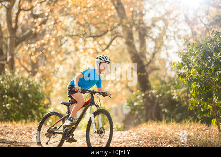 Boy mountain biking on path in woods Stock Photo