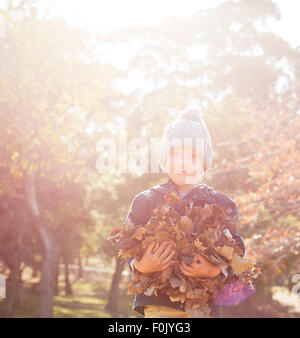 Portrait smiling boy holding bunch of autumn leaves Stock Photo