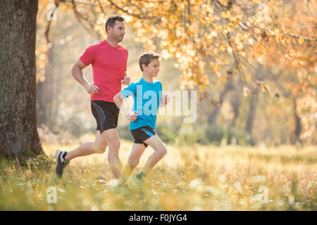Father and son jogging in autumn park Stock Photo